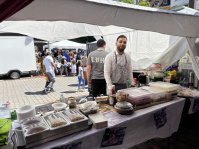 Ein Mann steht hinter einem Stand mit Essen.