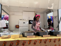 Eine Frau verkauft am Stand afrikanisches Essen.