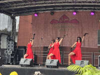 Vier Frauen in roten Kleidern tanzen Tango auf einer Bühne.