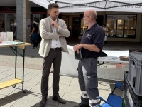Zwei Männer stehen unter einem Pavillon des Deutschen Roten Kreuzes und unterhalten sich.