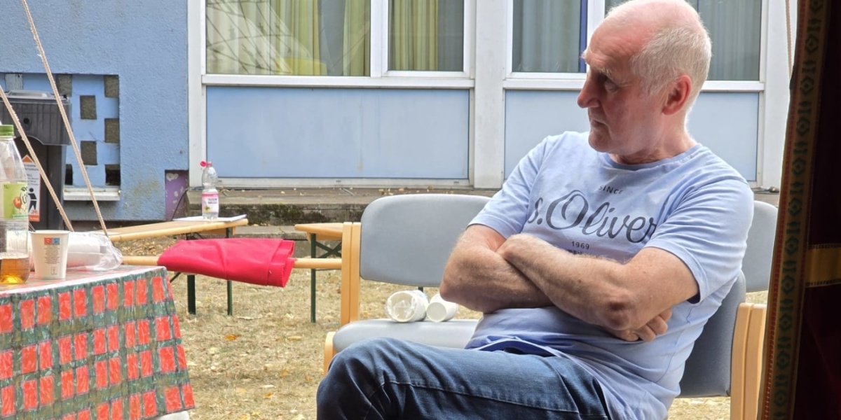 Ein Mann sitzt auf einem Stuhl und hört interessiert einem Gespräch zu