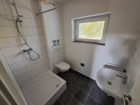 Bad mit Fenster, Dusche, wandhängendes WC, Waschtisch, teilgefliest weiß, graue Bodenfliesen